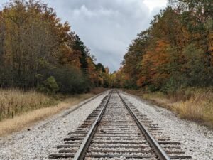 Railroad tracks stretching into the distance, flanked by autumn foliage in Michigan, highlighting rural landscapes relevant to Pure Broadband MI's internet service focus.